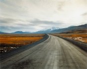 Estrada vazia que conduz a belas montanhas remotas no dia nublado — Fotografia de Stock