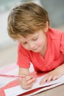 Young boy on floor painting with pen — Stock Photo