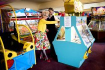 Pareja disfrutando en arcade de diversiones, Bournemouth, Inglaterra - foto de stock