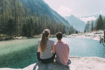 Vista posteriore di una giovane coppia di escursionisti che si affaccia sul lago di montagna, Lombardia, Italia — Foto stock
