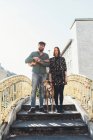 Portrait of cool couple with dog standing on footbridge — Stock Photo