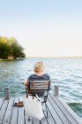 Жінка сидить на пірсі біля води — стокове фото