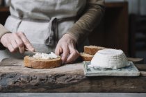 Frau verteilt Quark auf Scheibe Brot, Mittelteil — Stockfoto
