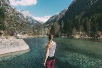 Вид сзади на молодую женщину, смотрящую на озеро — стоковое фото