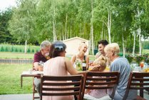 Familia de tres generaciones almorzando en la mesa del patio - foto de stock