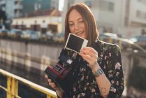 Young woman looking at instant photo by canal — Stock Photo