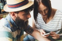 Paar schaut in Bar auf Smartphone — Stockfoto
