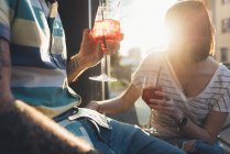 Обрізаний знімок пари, що сидить за межами сонячно освітленого тротуарного кафе з коктейлями — стокове фото