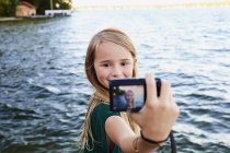 Chica tomando selfie por río - foto de stock