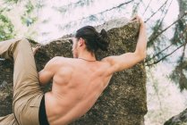 Rear view of male climbing on boulder edge — Stock Photo