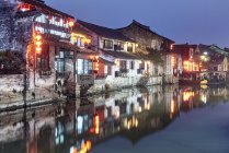 Vía navegable y edificios tradicionales al atardecer, Xitang Zhen, Zhejiang, China - foto de stock