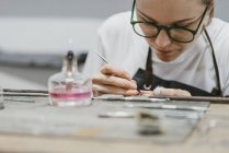 Vista de cerca del joyero femenino que trabaja con la herramienta de mano en miniatura en el banco de trabajo - foto de stock