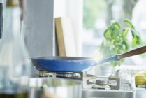 Синя сковорода на плиті на кухні — стокове фото