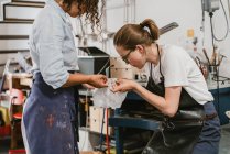 Женщины-ювелиры осматривают сложный продукт в ювелирной мастерской — стоковое фото