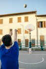 Rückansicht eines Mannes, der Basketball auf Basketballkorb wirft — Stockfoto