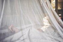 Bebê menina deitada na rede drapeado berço agarrando lençol — Fotografia de Stock