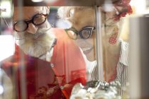 Quirky casal vintage olhando para vitrine de vidro em empório antigo — Fotografia de Stock