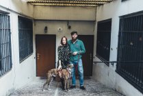 Portrait of cool couple with dog outside apartment — Stock Photo
