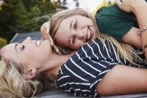 Mother and daughter lying on wooden decking outdoors — Stock Photo