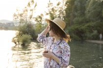 Young woman in straw hat beside lake — Stock Photo