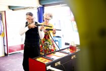 Quirky couple enjoying shooting gallery in amusement arcade, Bournemouth, England — Stock Photo