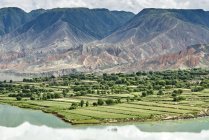 Vista elevada de las montañas y tierras agrícolas por el río Amarillo, Sichuan, China - foto de stock