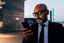 Mature businessman using smartphone at night — Stock Photo