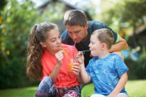 Homme mûr avec fille adolescente et fils partageant un smoothie frais dans le jardin — Photo de stock