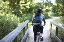 Вид сзади на женщину-велосипедистку, едущую через мост — стоковое фото