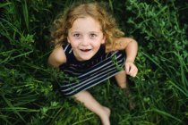Дівчина дивиться на камеру на зеленому трав'янистому полі — стокове фото