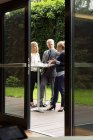 View through doorway of colleagues standing at patio table enjoying refreshments — Stock Photo