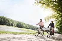 Зрелая пара катается на велосипеде у озера — стоковое фото