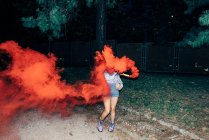 Femme tenant la fusée éclairante dans le parc la nuit — Photo de stock