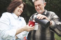 Mature couple pouring hot drink from drinks flask — Stock Photo