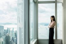 Femme d'affaires regardant par la fenêtre au paysage urbain — Photo de stock