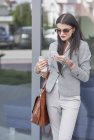 Femme d'affaires avec tasse à café en utilisant un smartphone — Photo de stock