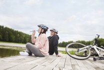 Mature couple with bicycles relaxing on jetty — Stock Photo