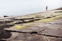 Mujer joven corriendo a lo largo del muro marino - foto de stock