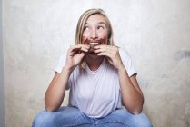 Retrato de mujer comiendo barra de chocolate, chocolate alrededor de la boca - foto de stock