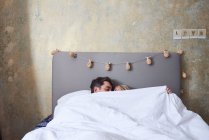 Пара в ліжку, під обкладинками, цілується — стокове фото