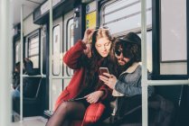 Молода пара сидить на поїзді метро, дивлячись на смартфон — стокове фото