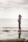 Junge Läuferin streckt am Strand die Arme aus — Stockfoto