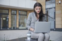 Femme d'affaires avec ordinateur portable et café en plein air — Photo de stock