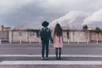 Young couple standing on road, holding hands, rear view — Stock Photo