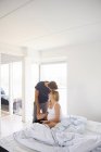 Мужчина целует беременную девушку в спальне — стоковое фото