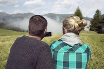 Visão traseira do casal no campo fotografando névoa, Tirol, Steiermark, Áustria, Europa — Fotografia de Stock