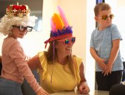 Mutter, Sohn und Tochter verkleiden sich, tragen lustige Hüte und Brillen, lachen — Stockfoto