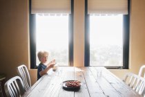 Niño sentado en la mesa de comedor mirando a la cámara, sorprendido, Fairfax, California, Estados Unidos, América del Norte - foto de stock