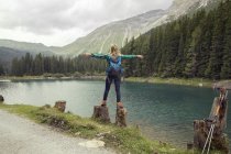 Rückansicht einer Frau, die auf Felsen am See balanciert, Tirol, Steiermark, Österreich, Europa — Stockfoto