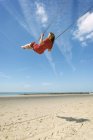 Woman in dress swinging on beach, Zoutelande, Zeeland, Netherlands, Europe — Stock Photo